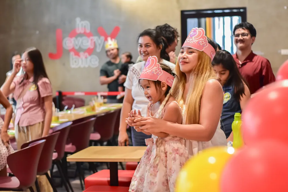 Kids wearing paper crowns with their families at a party venue