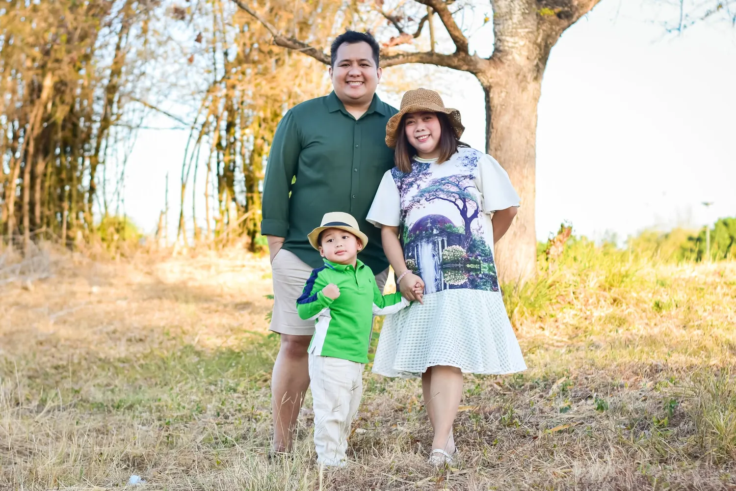 Parents and their toddler standing close together in warm golden-hour light during an outdoor family photoshoot by Dana Shotz