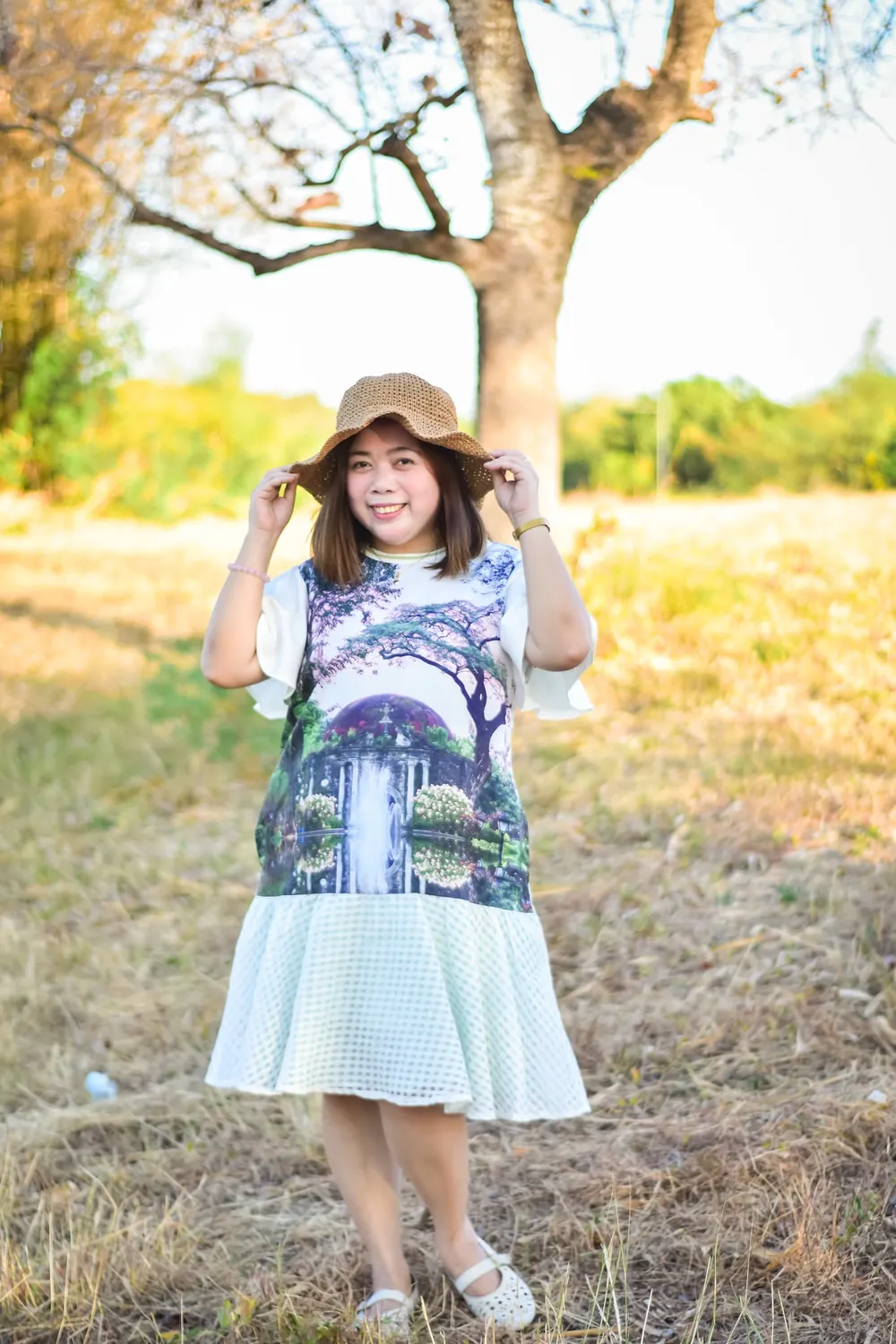 Mother in a straw hat smiling in a golden-hour field, outdoor portrait